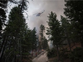 A helicopter flies overhead after dropping water outside a fire guard line as B.C. Wildfire Service firefighters conduct a controlled burn to help prevent the Finlay Creek wildfire from spreading near Peachland earlier this summer.