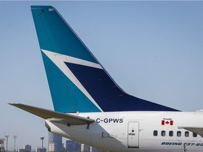 The tail of a WestJet plane is shown by the Calgary skyline.