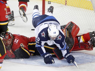 Winnipeg Jets Bryan Little collides with Calgary Flames goalie Mike Smith in NHL hockey action at the Scotiabank Saddledome in Calgary on Saturday October 7, 2017. Leah Hennel/Postmedia