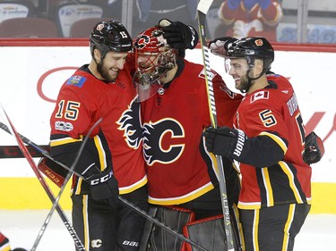 Calgary Flames goalie mike Smith, middle, is hugged by teammates Tanner glass, left and Mark Giordano, right after their 6-3 win over  Winnipeg Jets in NHL hockey action at the Scotiabank Saddledome in Calgary on Saturday October 7, 2017. Leah Hennel/Postmedia