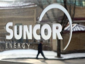 A pedestrian is reflected in a Suncor Energy sign in Calgary.