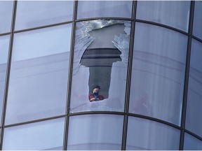 Firefighters assess a broken window high on the Brookfield Place building in downtown Calgary on Sunday October 15, 2017.  The damage rained glass down onto streets below in forcing the closure of several blocks below on Sunday October 15, 2017.
