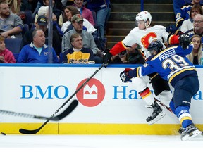 The Calgary Flames' Mark Jankowski (left) reaches for the puck as he is checked by the St. Louis Blues' Nate Prosser (No. 39) during the first period of an NHL hockey game Wednesday, Oct. 25, 2017, in St. Louis.