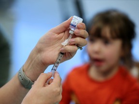 Celeste Bird 3, watches as her flu vaccination is prepared at the South Health Calgary Health Centre on the first day of immunization clinics across the city, Monday October 23, 2017. Gavin Young/Postmedia