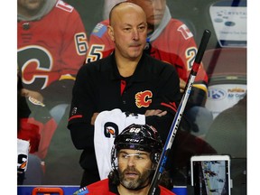 The Flames' Jaromir Jagr sits on the bench in front assistant equipment manager Corey Osmak during NHL hockey at the Scotiabank Saddledome in Calgary on Friday, October 13, 2017.
