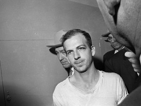 In this Nov. 23, 1963 file photo, Lee Harvey Oswald is led down a corridor of the Dallas police station for another round of questioning in connection with the assassination of U.S, President John F. Kennedy.