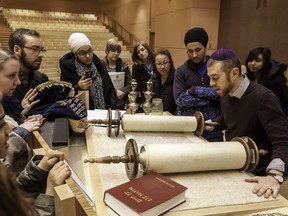 Students view a sacred torah scroll with Rabbi Joshua Corber at the Beth Tzedec Calgary Synagogue.