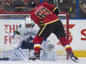 Flames prospect Adam Ruzicka (right) fires a shot past goalie Vancouver Canucks Michael DiPietro for a goal during NHL preseason hockey action at the Young Stars Classic held at the South Okanagan Events Centre in Penticton, B.C.
