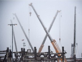 Cranes work on the Aecon site in the falling snow in northeast Edmonton on Nov. 3, 2015.