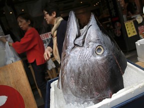 Customers walk past the head of a bluefin tuna in front of a seafood restaurant at Tsukiji fish market in Tokyo.