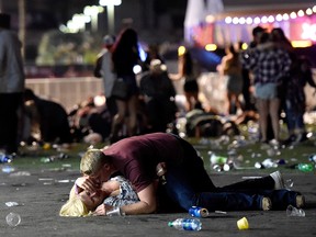 LAS VEGAS, NV - OCTOBER 01:  A man lays on top of a woman as others flee the Route 91 Harvest country music festival grounds after a active shooter was reported on October 1, 2017 in Las Vegas, Nevada. A gunman has opened fire on a music festival in Las Vegas, leaving at least 2 people dead. Police have confirmed that one suspect has been shot. The investigation is ongoing. (Photo by David Becker/Getty Images)