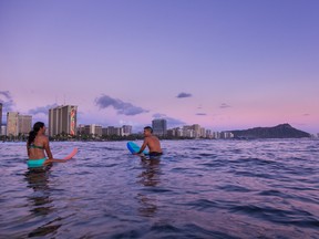 Heading out for a surf session at dusk on Waikiki Beach.