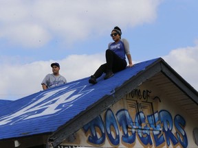 Los Angeles Dodgers fans take photos on a blue-painted single home roof, painted by South Los Angeles artist and Dodger fan Hector "Tetris" Arias, so the World Series theme house would be visible from the air in South Los Angeles, Wednesday, Nov. 1, 2017. The Houston Astros and Los Angeles Dodgers are keeping their lineups intact for the deciding Game 7 of the World Series. The Dodgers won 3-1 on Tuesday night to tie it up 3-all and force the first World Series Game 7 in Dodger Stadium history. (AP Photo/Damian Dovarganes)