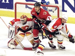 Calgary Flames goalie Fred Brathwaite tracks the puck, with help from defender Bobby Bollas, during a game against the Ottawa Senators in 1999.