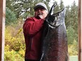 Ted Walkus, hereditary chief with the Wuikinuxv First Nation, hoisting up a particularly large Chinook from the Wannock River.