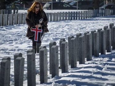 Lyn Moehling looks for the grave marker of her grandfather, WWI veteran Noble Edgar Taggart, following a Remembrance Day service in Calgary, Saturday, Nov. 11, 2017.