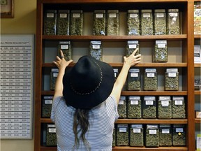 An employee arranges glass display containers of marijuana on shelves at a retail and medical cannabis dispensary in Boulder, Colo.