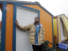 Tyson King stands at the door of his tiny house, where he has lived for nearly seven weeks, at a homeless encampment in Seattle.