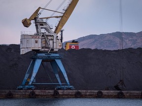 A photo taken on November 21, 2017 shows a mound of North Korean coal adjaecent to the the RasonConTrans coal port at Rajin harbour in the Rason Special Economic Zone. A mountain of North Korean coal -- which would once have been bound for China -- is piled up on one side of the barrier in Rajin harbour, stranded by a UN ban on coal exports by Pyongyang. On the very next dock, around two million tonnes of Russian coal have come in by train and been shipped on to China this year by Russian port operator RasonConTrans. Its activities are specifically excluded from the UN Security Council's sanctions resolutions  but attempts have been made to use it as a way to bypass the restrictions.