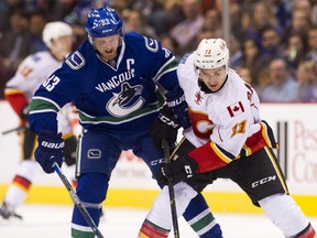 Henrik Sedin #33 of the Vancouver Canucks and Mikael Backlund #11 of the Calgary Flames get tangled up while battling for the puck in NHL action on October, 10, 2015 at Rogers Arena in Vancouver, British Columbia, Canada.