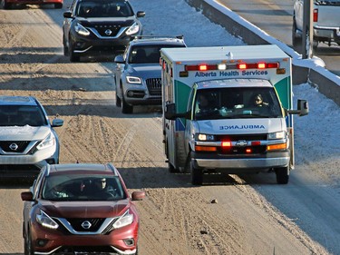 An ambulance drives with lights and sirens on a snowy Glenmore Trail on Wednesday December 20, 2017. An overnight winter storm hit Calgary lead to multiple crashes around the city.