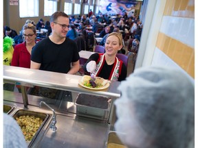 Volunteer Sarah Tubman adds cranberry sauce as fellow volunteers line up to serve a turkey lunch at the Calgary Drop-In Centre on Christmas Day in Calgary 2017. The meal was sponsored by Luke's Drug Mart and Progress Energy. Gavin Young/Postmedia