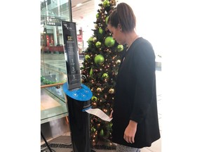 Megan Hall takes a printout from a short story dispenser at Edmonton International Airport in a handout photo.