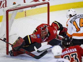 Philadelphia Flyers' Sean Couturier, right, has his shot deflected by Calgary Flames goalie Mike Smith during second period NHL hockey action in Calgary, Monday, Dec. 4, 2017.