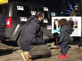 Ali Fneich and his two-year-old son Mohammed look at a missing persons poster of 32-year-old Nadia Atwi at Churchill Square on Sunday, Dec. 18, 2017.