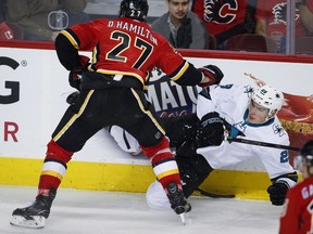 San Jose Sharks' Timo Meier is checked by Calgary Flames blueliner Dougie Hamilton during second period NHL hockey action in Calgary on Thursday. Photo by Jeff McIntosh/The Canadian Press.