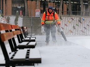 A city worker clears snow at Olympic Plaza on Tuesday, Dec. 19, 2017.