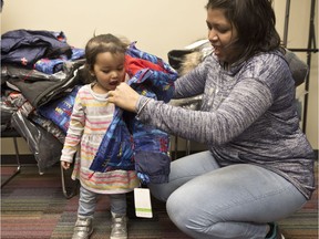 Sampa Maiti and her daughter Aashi, 2, try on new winter coats at the Centre for Newcomers in Calgary. The family arrived from India three months ago. Leah Hennel/Postmedia