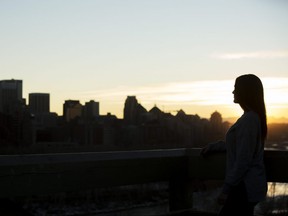 A 27-year-old female sexual assault survivor, who can't be identified, is silhouetted against the city skyline while standing atop of the McHugh Bluff staircase on Friday, Dec. 8, 2017 in Calgary, Alta.
