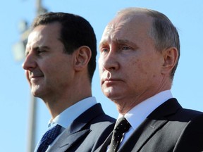 Russian President Vladimir Putin, right, and Syrian President Bashar Assad watch the troops marching at the Hemeimeem air base in Syria, on Monday, Dec. 11, 2017. Declaring a victory in Syria, Putin on Monday visited a Russian military air base in the country and announced a partial pullout of Russian forces from the Mideast nation.