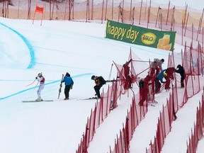 Lindsey Vonn, left, gets back on course, as workers repair the netting, after she crashed during the FIS Ski World Cup Women's Downhill on December 1, 2017 in Lake Louise.