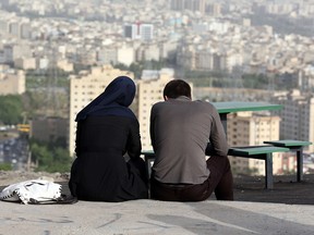 An Iranian couple sit together in the northwestern Shahran neighbourhood overlooking Tehran on June 7, 2014.