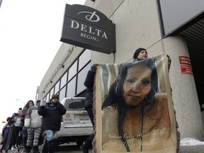 Delores Stevenson, right, leads a rally while holding a blanket showing the face of her niece Nadine Machiskinic, outside the Delta Hotel in Regina, Sask. on Sunday January 10, 2016.