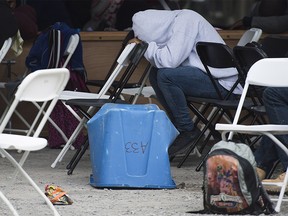 An asylum seeker rests his head at a makeshift processing centre at the Canada-United States border on Roxham Road in Hemmingford, Que. Wednesday, August 9, 2017. Twenty officials from the Immigration and Refugee Board have been assigned to focus exclusively on processing the asylum claims of people crossing illegally into Quebec. THE CANADIAN PRESS/Graham Hughes ORG XMIT: GMH500