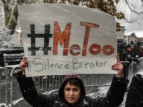 People carry signs addressing the issue of sexual harassment at a #MeToo rally.