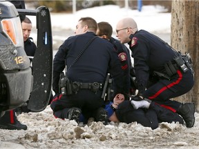 Calgary police take a male suspect into custody near 37 Street and Bow Trail S.W. on Saturday.