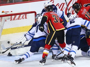 Calgary Flames and Winnipeg Jets players pile up in front of the Jets's net after a goal that was eventually ruled no goal due to interference during NHL action at the Scotiabank Saddleome in Calgary on Saturday  January 20, 2018.