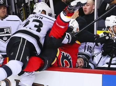The Los Angeles Kings' Torrey Mitchell checks Calgary Flames captain Mark Giordano into the bench during NHL action in Calgary on Wednesday January 24, 2018.  LA won 2-1 in overtime.