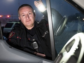 District 5 community resource officer Const. Colin Thorne peeks inside idling vehicles during Operation Cold Start in Calgary on Jan. 9 2017.