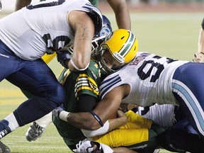 Toronto Argonauts' Cleyon Laing and Ivan Brown hit Edmonton Eskimos quarterback Mike Reilly during first half action in Edmonton, on Sept. 28, 2013. Reilly sustained a helmet-to-helmet hit on this play and was diagnosed with a concussion.
