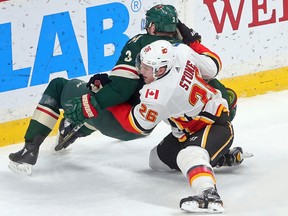 The Calgary Flames' Michael Stone (right) brings down Minnesota Wild's Charlie Coyle in the first period of an NHL hockey game Tuesday, Jan. 9, 2018, in St. Paul, Minn.