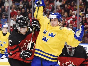 Linus Lindstrom battles with Team Canada defender Kale Clague during the World Junior Championship gold medal game on Jan. 5.