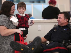 Acting Deputy Chief Cliff O'Brien gives blood at the blood donor clinic in Calgary, on Thursday January 4, 2018, as Journey Dickson, 6, who gets transfusions every month, looks on with his mom Coriena.  Leah Hennel/Postmedia