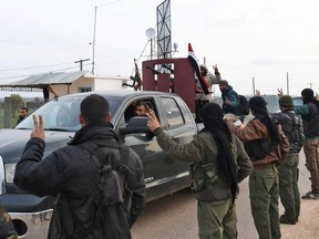 A picture taken on February 20, 2018 shows Kurdish fighters flashing the victory gesture as they welcome a convoy of pro-Syrian government fighters arriving in Syria's northern region of Afrin.