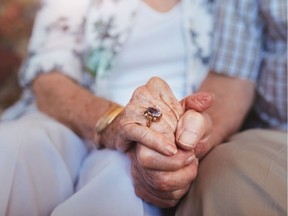 Cropped shot of elderly couple holding hands while sitting together at home. Focus on hands. Getty Images/iStockphoto