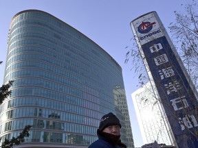A man walks past the headquarters of the state-owned China National Offshore Oil Corp. (CNOOC) in Beijing.
